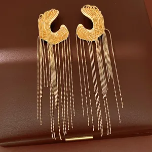 Close-up of elegant gold irregular earrings with long bead chain tassels