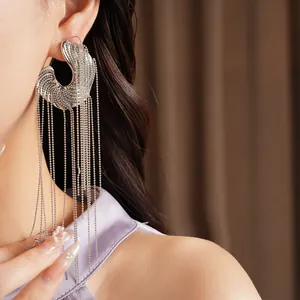 Macro shot of long silver tassel earrings with irregular textured crescent design