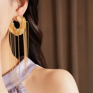 Close-up of irregular gold tassel earrings with long delicate bead chains.