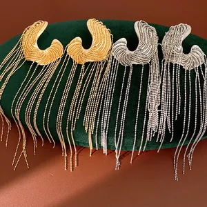 Detailed view of irregular wavy gold and silver earrings with long beaded chain tassels