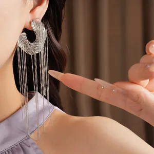 Detail view of silver-tone irregular wavy earrings with long ball chain tassels