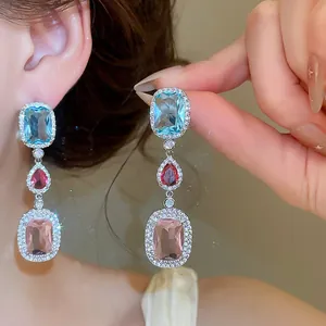 Detailed close-up of elegant silver needle dangle earrings with multicolor zircon stones