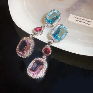 Macro detail of multi-colored zircon earrings with blue, red, and purple gemstones