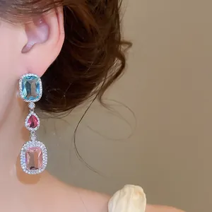 Detail view of elegant silver drop earrings with colorful zircons worn on model