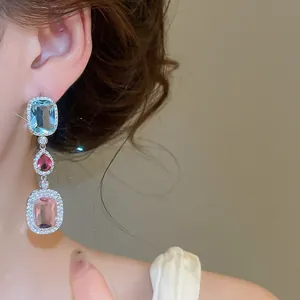 Close-up of elegant silver dangle earrings with colorful oval and teardrop zircon stones