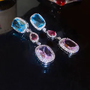 Close-up of elegant zirconia drop earrings with colorful gemstones for gala evening wear.