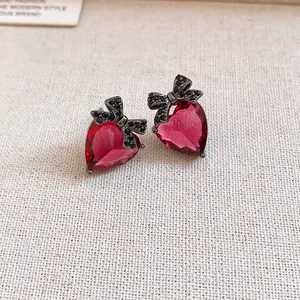 Detailed macro view of vintage red heart stud earrings with a black zircon bow
