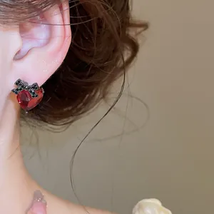 Close-up of retro red heart stud earrings with black bow detail and zircon.