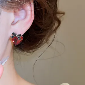Close-up view of elegant red heart zircon stud earring with black bow detail worn on ear.