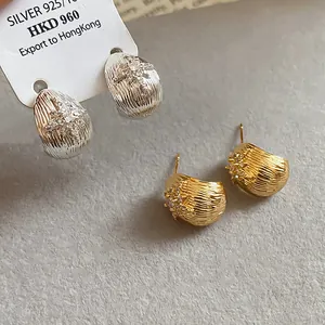 Detailed view of silver and gold plated floral stud earrings with cubic zirconia.