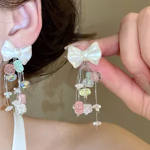 Vue détaillée de boucles d'oreilles nœud blanc avec pampilles en cristal coloré
