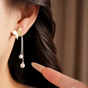 Nahaufnahme eleganter Schmetterlingsohrringe mit Perlenanhängern an einem asiatischen Model