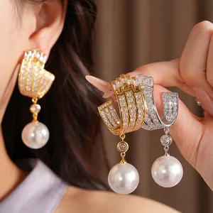 Elegant gold and silver U-shaped earrings with zirconia stones and large white pearls.