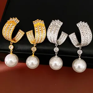 Detailed view of geometric U-shaped earrings inlaid with zircons and large pearls