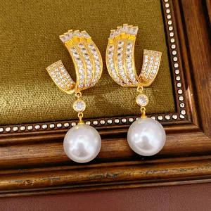 Close-up detail of luxurious gold U-shaped earrings featuring shimmering zircons and white pearls