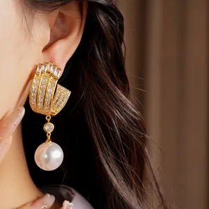 Detailed shot of luxury geometric gold earrings featuring cubic zirconia and a large white pearl