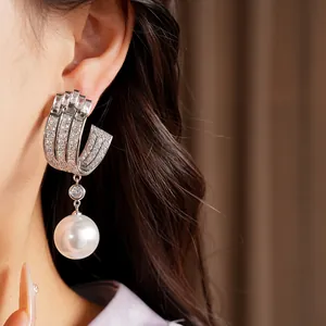 Close-up detail showing the sparkle of geometric U-shaped zircon earrings with large white pearl