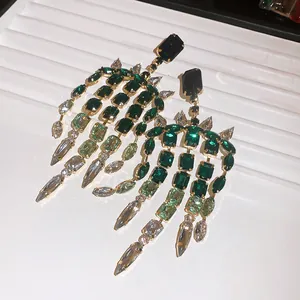Dettaglio di orecchini a nappa con cristalli verde smeraldo su vassoio espositore bianco