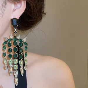Eleganti orecchini a nappa in strass verde smeraldo con un primo piano degli scintillanti perni