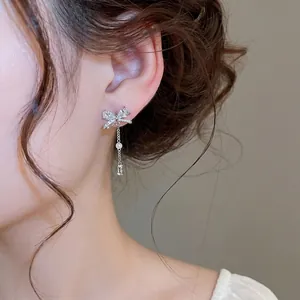 Elegante Zirkonia Schleifen Quasten Ohrringe mit Perlendetail am Ohr des Models