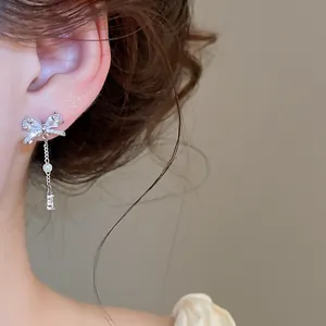 Detailansicht eines eleganten silbernen Schleifenohrrings mit Zirkonia-Quaste am Ohr