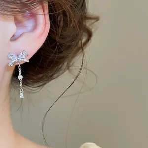 Detailansicht eines funkelnden Zirkon-Schleifen-Ohrrings mit Quasten am weiblichen Ohr