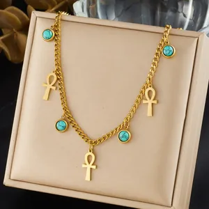 Detailed view of a gold-plated Ankh and turquoise pendant necklace on a display.