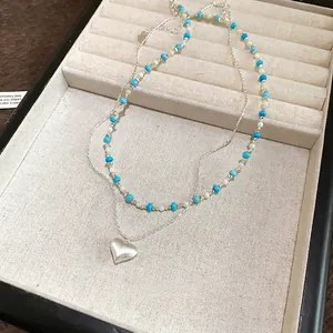 Close-up view of a vintage turquoise beaded layered necklace with a silver heart pendant