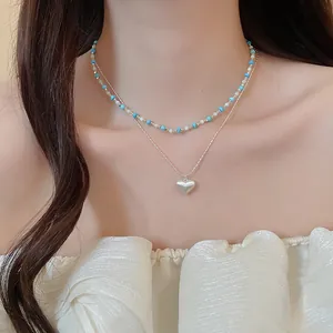 Detail shot of a French vintage turquoise beaded necklace with a silver heart pendant.