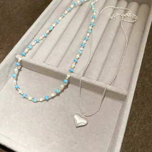 Detailed view of a vintage turquoise beaded necklace and a silver heart pendant chain.