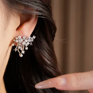 Detail shot of elegant silver zircon and pearl ear clip with star motifs on model's ear