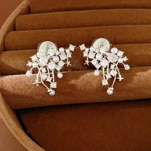 Detail view of elegant zircon and teardrop pearl ear clips on velvet background