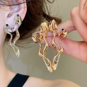 Detailed view of unique irregular hollow-out earrings in gold and silver finish.