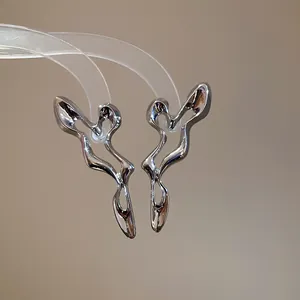 Detailed macro view of irregular hollow silver stud earrings with unique liquid metal design.