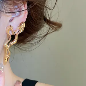 Detailed view of unique golden irregular hollow stud earrings worn on a model's ear