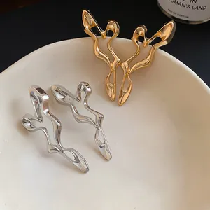Detailed close-up of the fluid organic design on the gold and silver irregular earrings