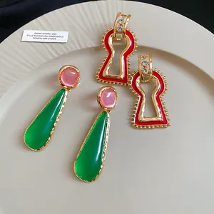 Detail view of vintage geometric metal earrings in green drop and red keyhole shapes.