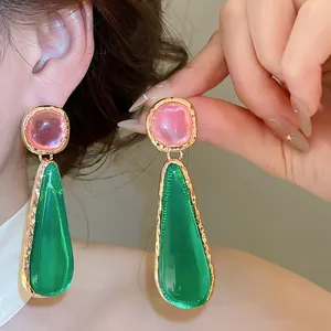 Detailed close-up of vintage pink and green geometric drop earrings with gold trim