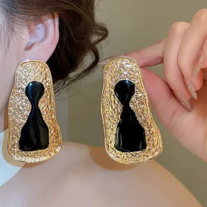 Close-up of vintage geometric gold and black irregular metal stud earrings on model.