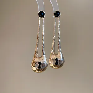 Close-up of vintage irregular gold-toned metal earrings with a black keyhole design