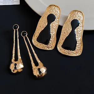 Detailed view of vintage gold geometric metal earrings featuring artistic black enamel accents