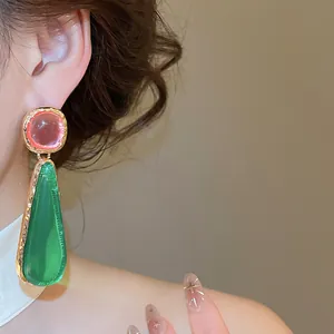 Macro detail of a vintage-style earring with pink and green stones in gold metal