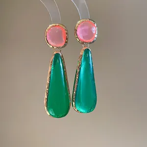 Macro view of vintage green and pink translucent resin teardrop earrings with gold rim