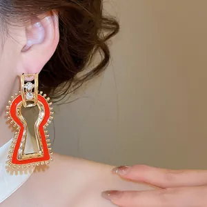 Close-up of artistic vintage gold earrings with red enamel and crystal detailing