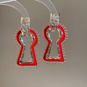 Detail view of vintage keyhole earrings featuring red enamel and gold accents