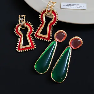 Detailed view of vintage geometric red keyhole and green teardrop enamel earrings