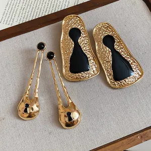 Close-up of vintage geometric metal earrings with black enamel and hammered texture.