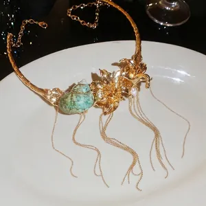 Detailed view of a gold floral necklace featuring a turquoise conch and elegant long tassels.