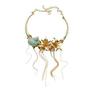 Statement gold flower seashell necklace with long tassel chains on a pure white background.