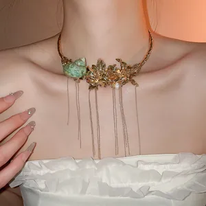 Close-up of golden floral collar necklace with green sea snail and pearl details.